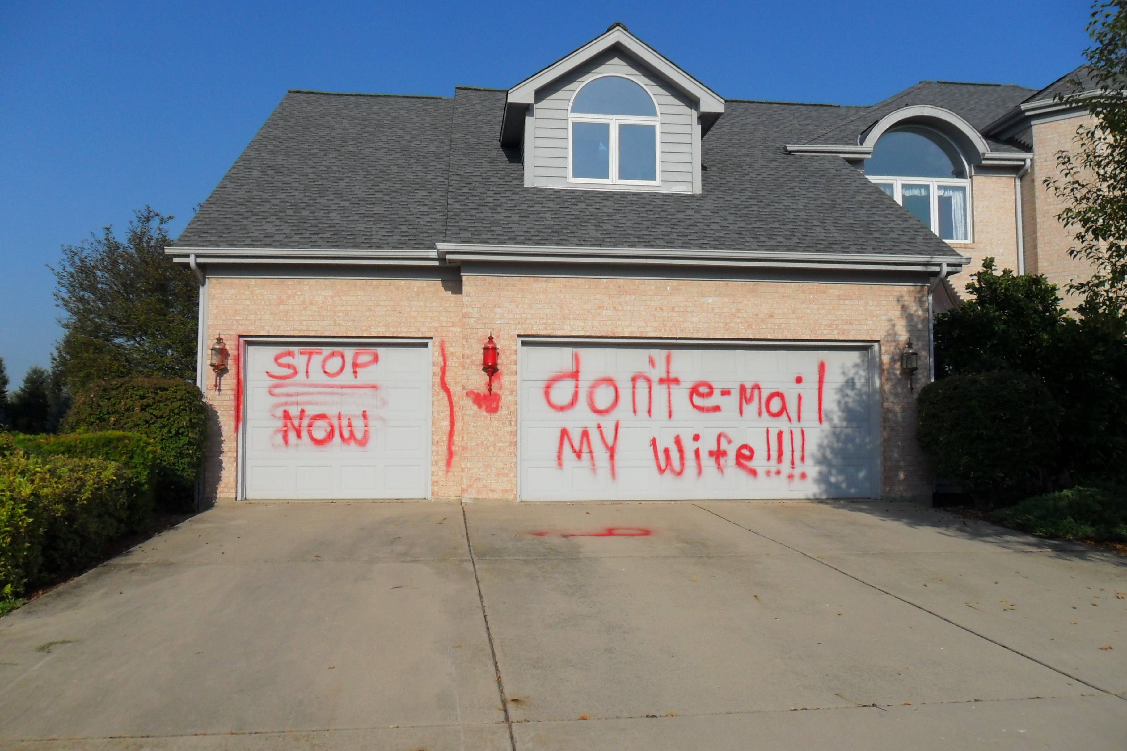 image of a suburban home with grafitti on the garage doors reading STOP NOW - DON'T EMAIL MY WIFE